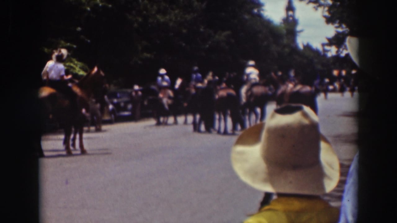 1937 Truckee home-movie frame with riders, horses, spectators, and parked automobiles along a shaded road.