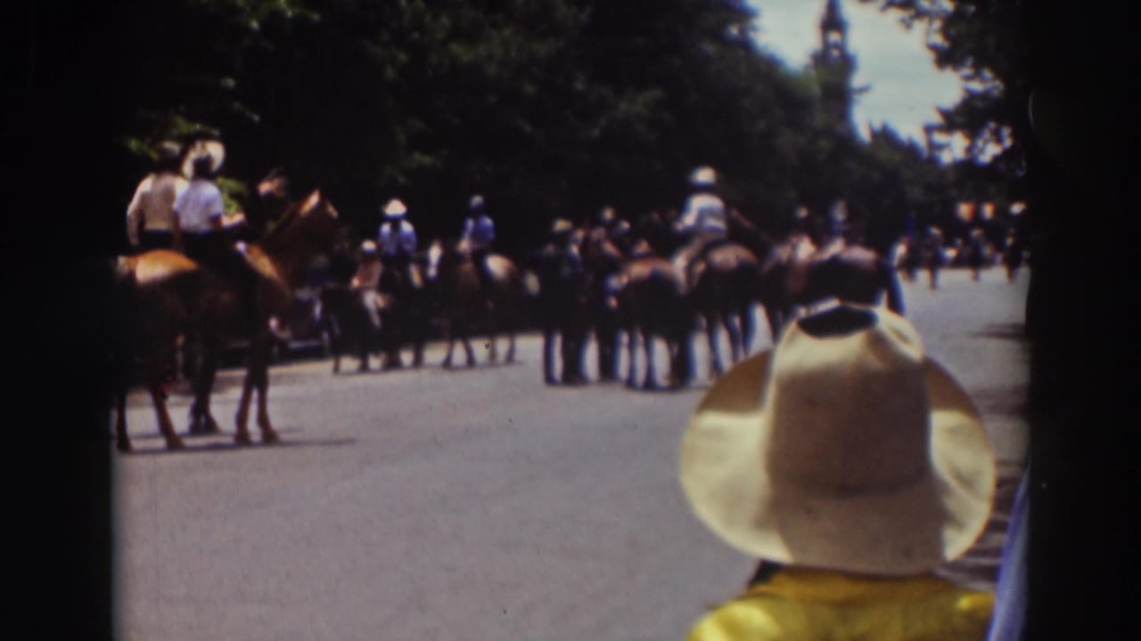 1937 Truckee 8mm frame showing horseback riders clustered on a road while a spectator in a cowboy hat watches from foreground.