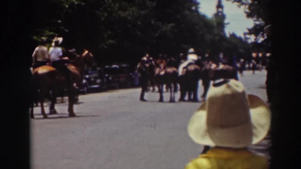 1937 Truckee parade view with a child in a wide-brimmed hat in the foreground and riders on horseback ahead.