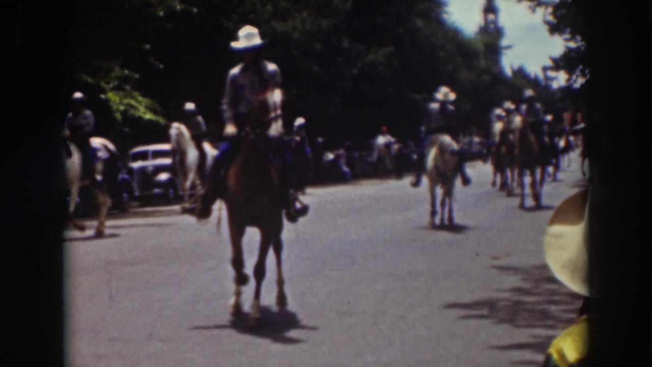 1937 Truckee parade frame showing a rider on horseback near the camera, with more mounted riders and spectators down the street.