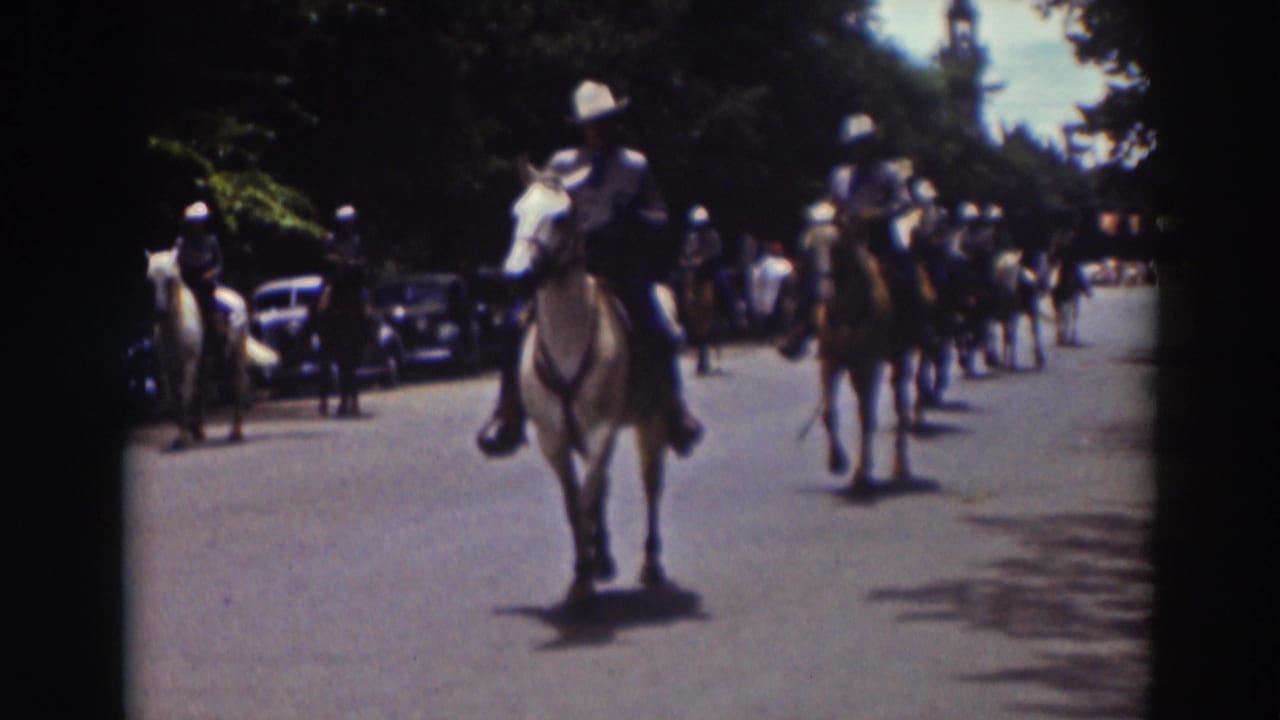 A white-shirted rider on a light horse leads part of the 1937 Truckee parade, with more horses and parked cars visible behind.