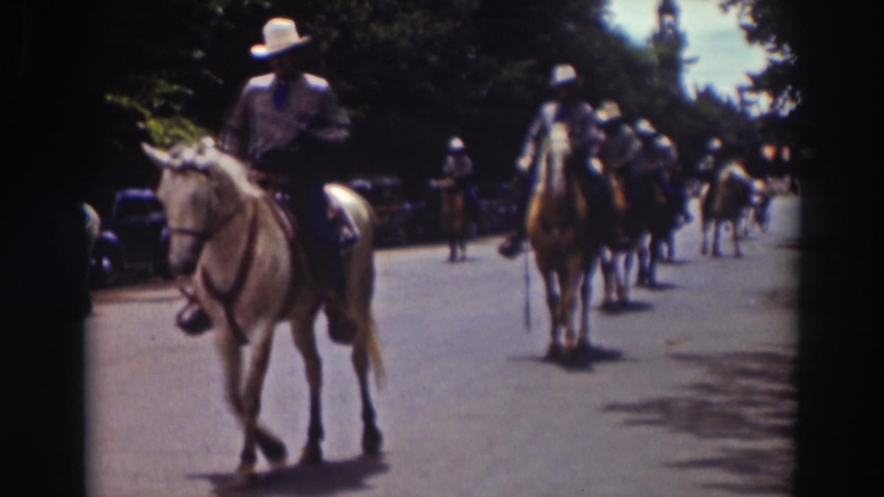In the Truckee parade scene, a mounted rider passes near the camera as additional riders continue down the sunlit street.