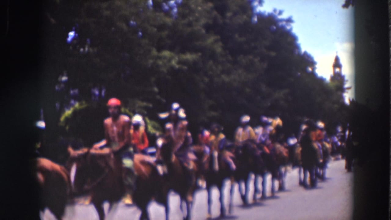 Adult riders in colorful costume move past spectators on a paved road in the Truckee, California parade footage.
