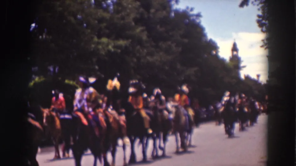 The parade line continues with costumed riders on horseback passing through Truckee, framed by trees and a bright sky.