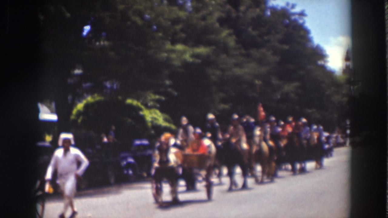 Horse-drawn buggies and mounted riders proceed through Truckee, California, with trees and parked cars visible along the road.