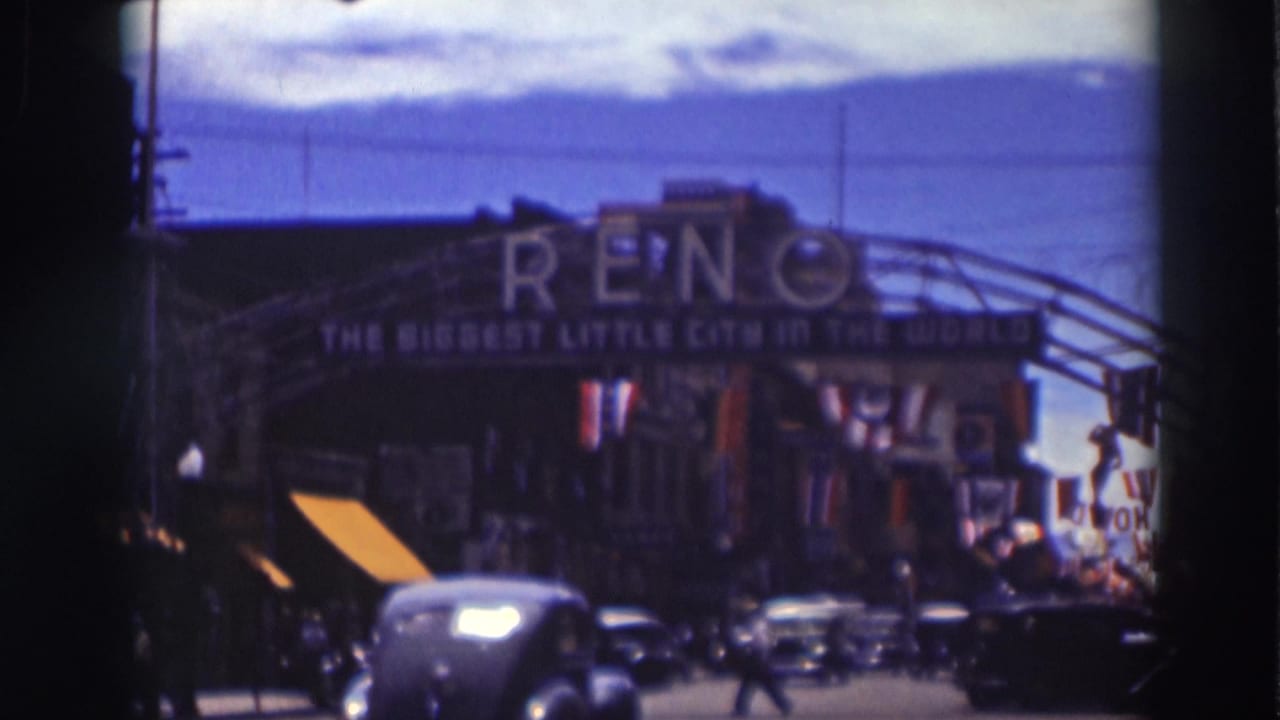 Street traffic passes beneath the Reno arch sign with storefronts and awnings below.
