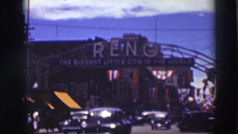 Reno entrance arch spans a busy 1937 street scene, with several cars, pedestrians at left, flags, and decorative bunting.