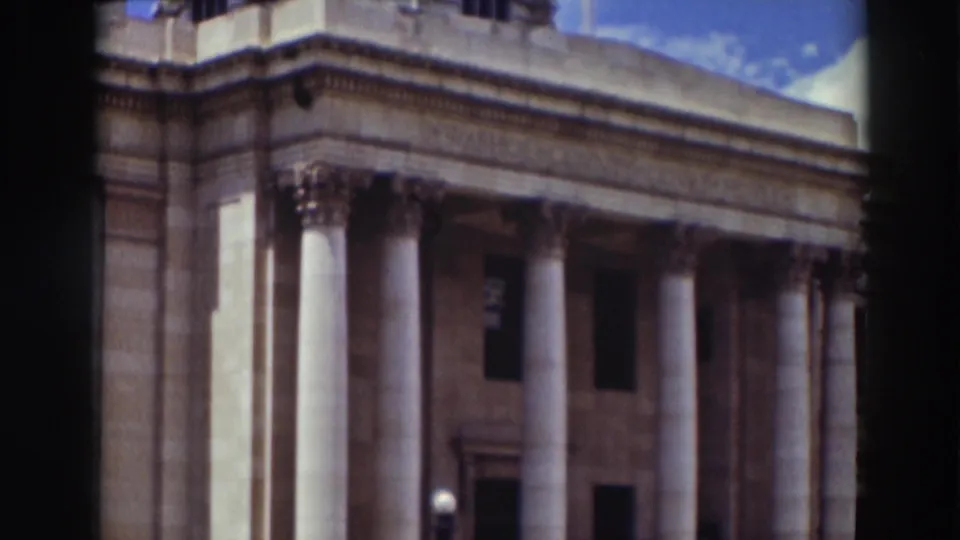 The final frame shows a diagonal view of the columned stone facade, emphasizing the building's classical architecture and upper windows.