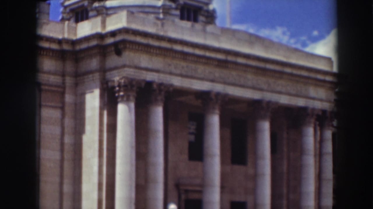 1937 Truckee home-movie frame showing a government building facade with tall columns, ornate capitals, and the lower edge of a dome.