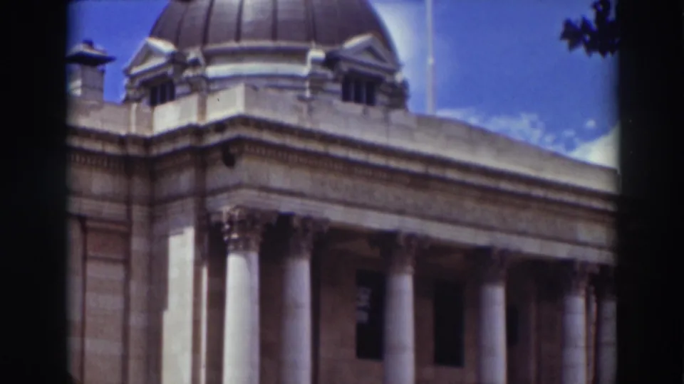 1937 Truckee frame with the government building dome, columned front, stone cornice, and bright blue sky visible above the facade.
