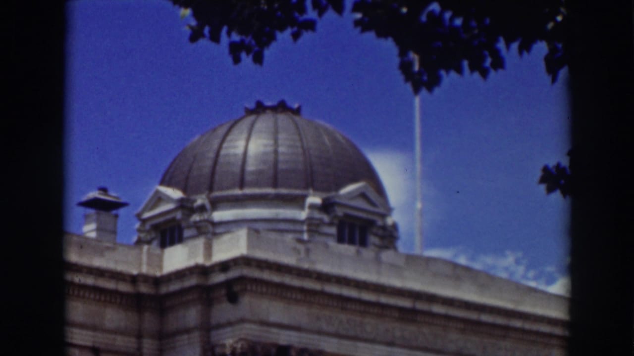 1937 Truckee frame with the domed roof and upper facade of a classical building, partially bordered by tree silhouettes.