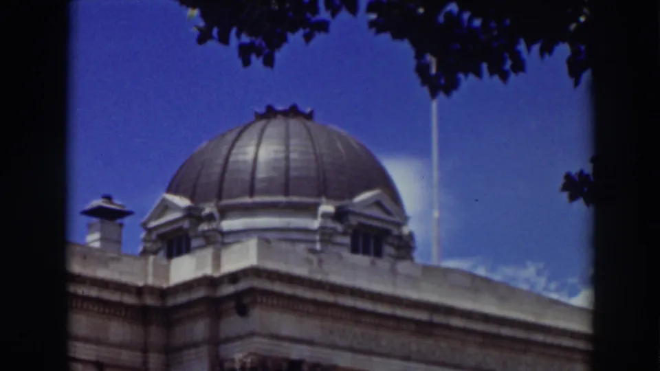 1937 Truckee frame with the domed roof and upper facade of a classical building, partially bordered by tree silhouettes.