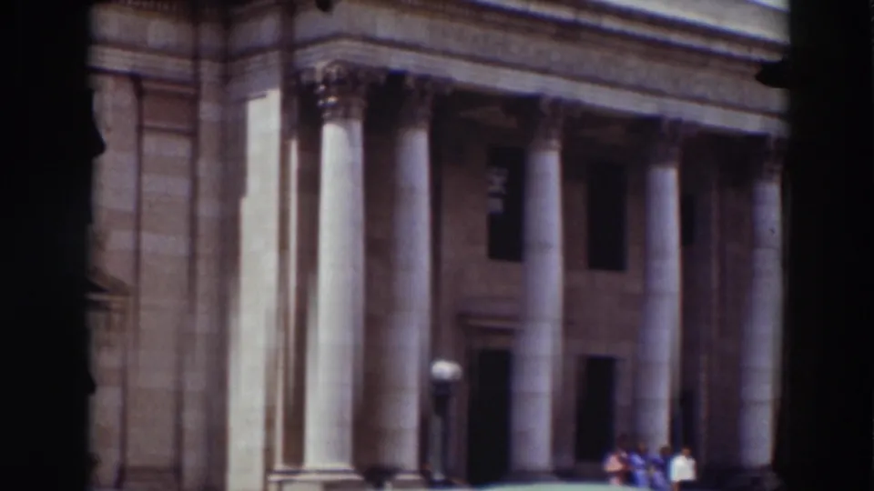 1937 home-movie view of the Washoe County Courthouse facade in Truckee, with tall columns and small figures near the entrance.