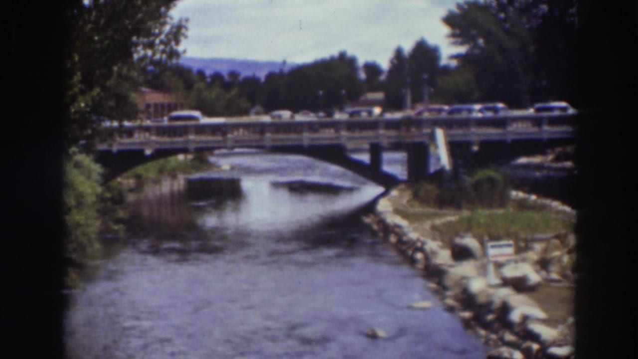 1937 Truckee home-movie view of the bridge, stream, riverside rocks, trees, and period cars passing across.