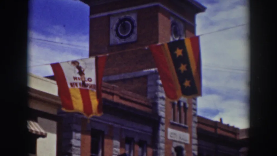 Truckee facade from 1937 with American flags, a red-and-yellow banner, a vertical star banner, and a circular detail near the roofline.