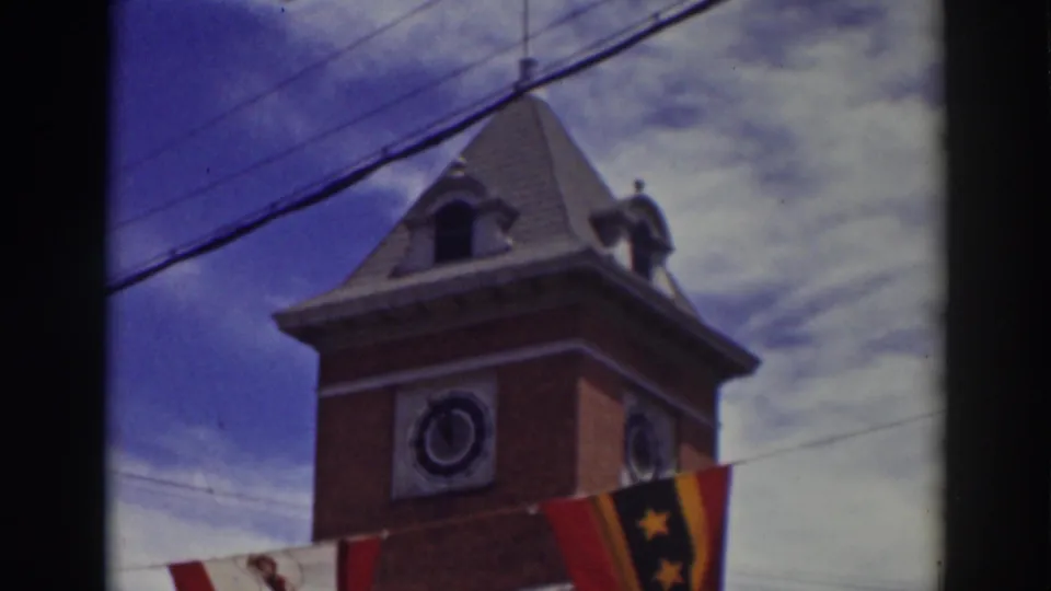 Final frame shows the upper Truckee clock tower, dark roof, round clock face, hanging flags, power lines, and mottled clouds.
