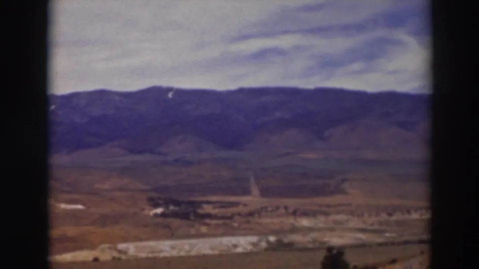 1937 8mm view of the Truckee, California area showing an open valley, road, distant hills, and clouded sky.