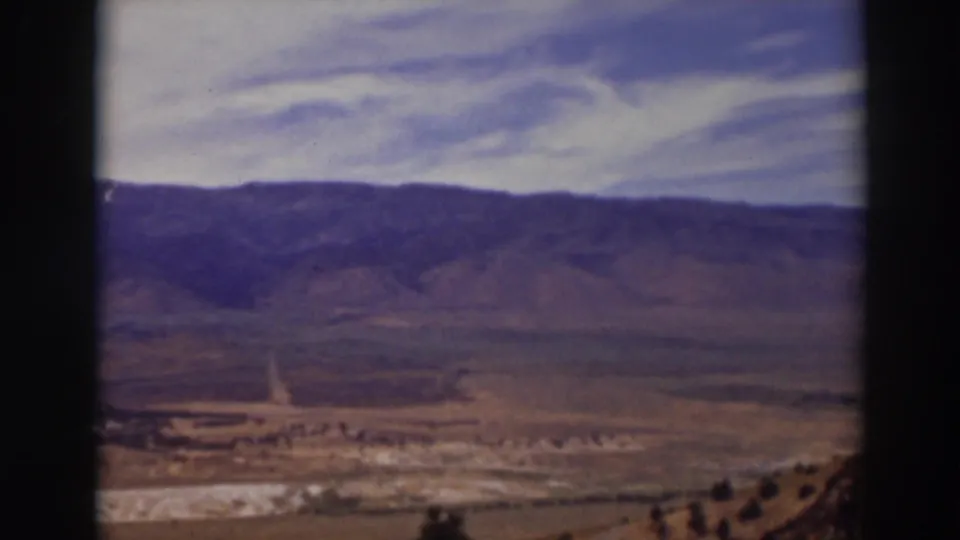 Late-1930s 8mm frame from Truckee, California, showing a remote valley, hillside slopes, and clouded sky.