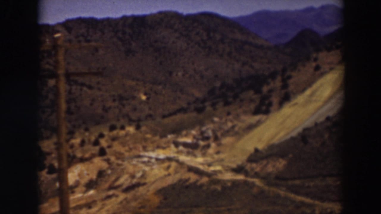 Dry mountain hills with a winding dirt road and distant blue ridges.