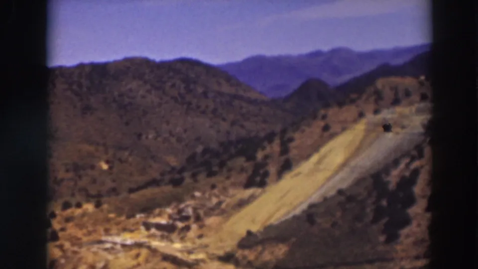 1937 8mm view in Truckee, California, looking over dry hill country toward a pale road and hazy mountain backdrop.