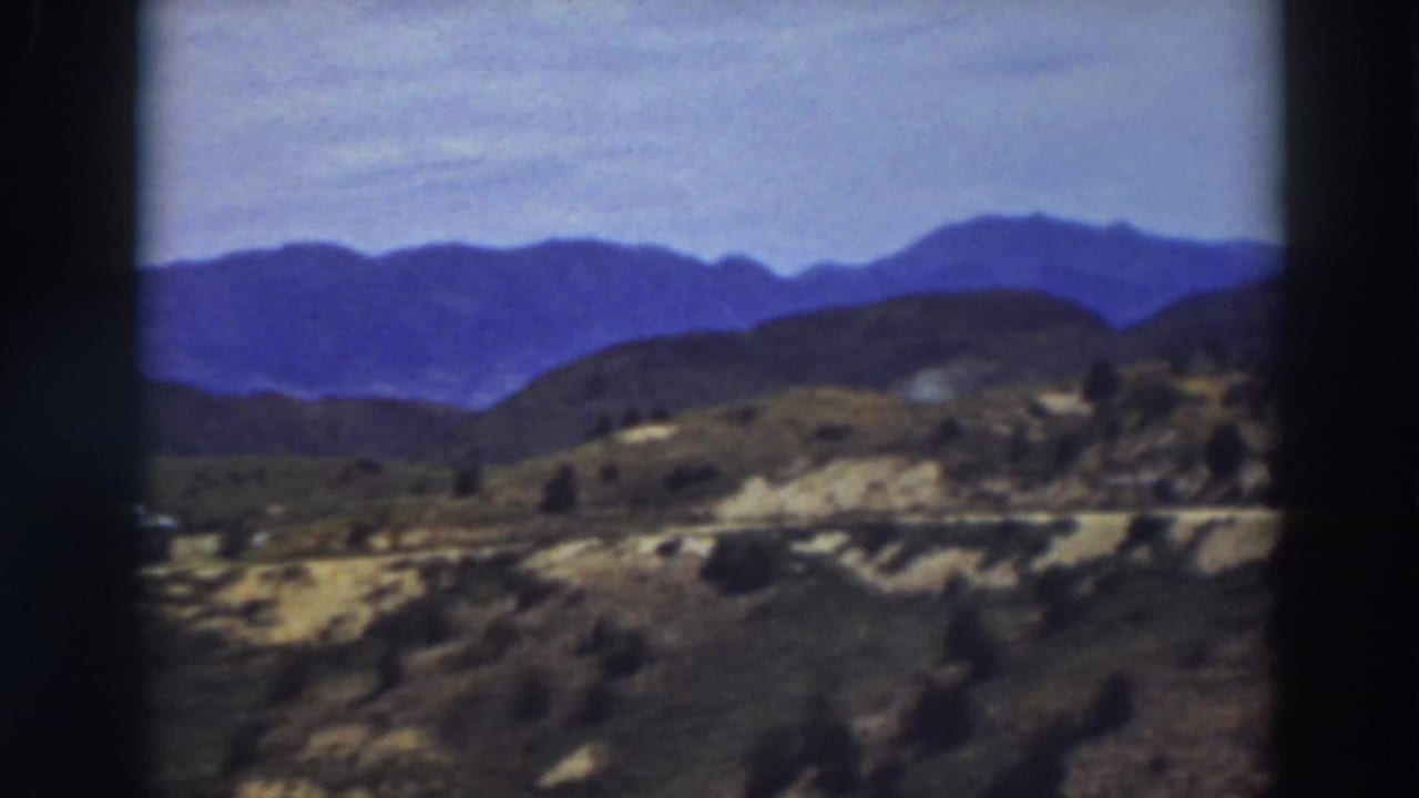 Truckee, California landscape frame with layered blue mountains, scrub-covered slopes, and a light road across the mid-ground.