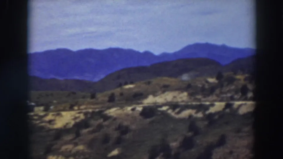 Truckee, California landscape frame with layered blue mountains, scrub-covered slopes, and a light road across the mid-ground.