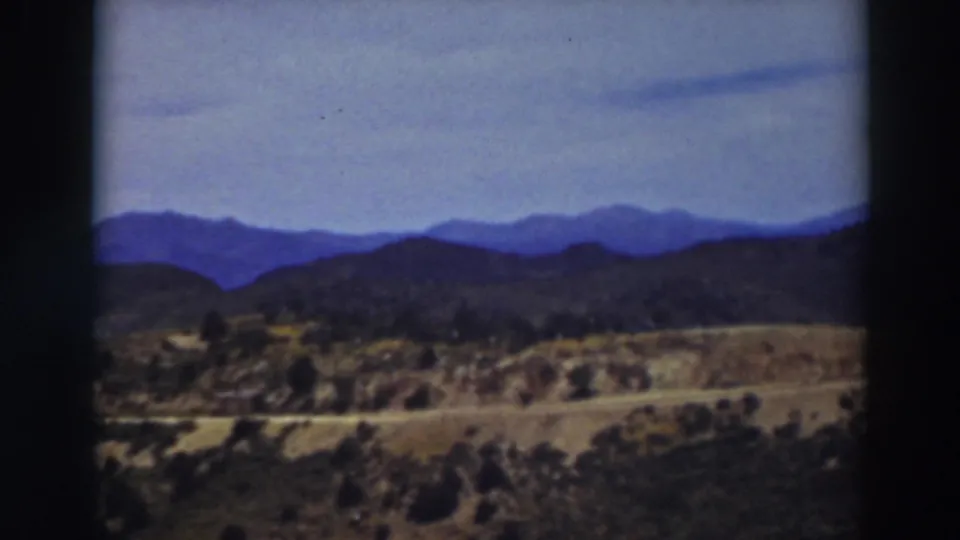 Final Truckee landscape frame showing open scrubland, low hills, a light-toned road, and distant blue mountain ridges.
