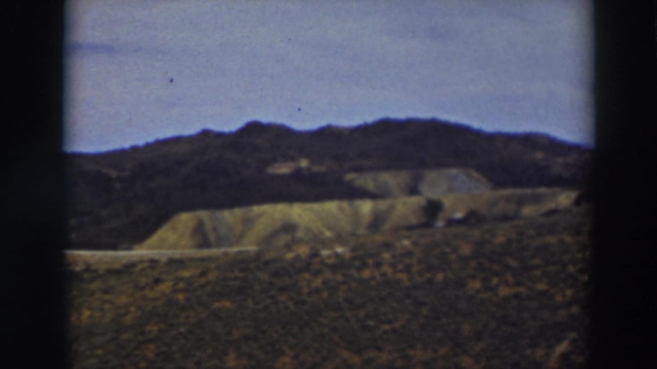 Truckee-area 8mm frame showing a darker ridgeline above pale eroded slopes and scrubby foreground terrain.