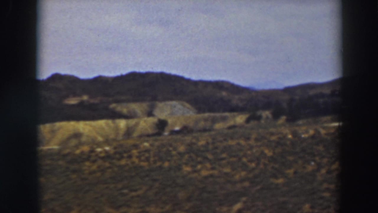 Truckee-area rural landscape in 1937, showing golden slopes, darker mountain ridge, and small distant buildings.