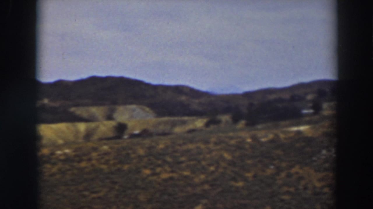 A soft 8mm frame of dry foreground grass, rolling Truckee hills, and a low ridgeline beneath a pale sky.