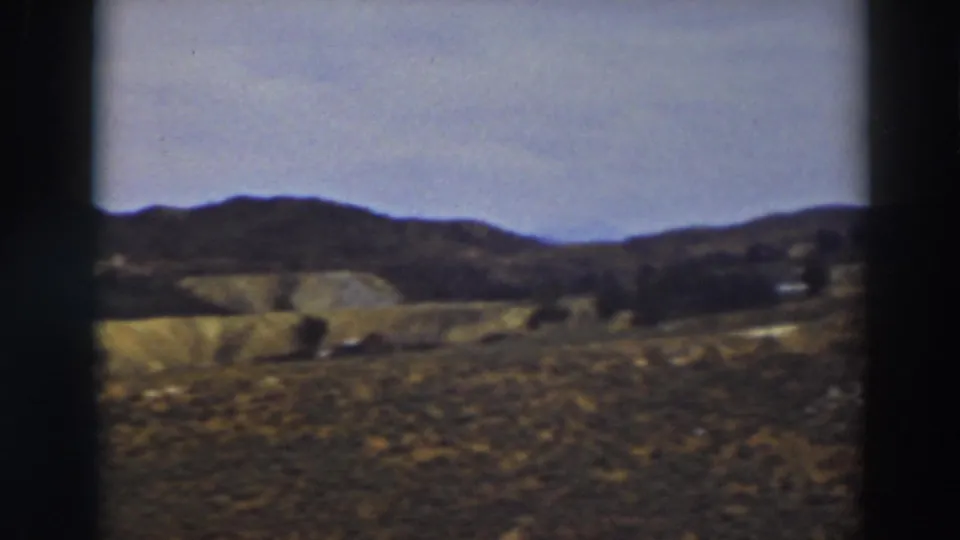 A soft 8mm frame of dry foreground grass, rolling Truckee hills, and a low ridgeline beneath a pale sky.