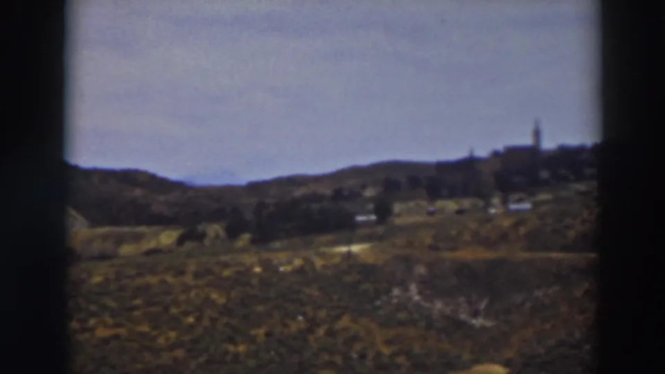 1937 Truckee-area hillside view with scrub vegetation, rolling terrain, and a small distant settlement marked by a steeple.