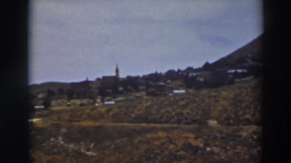 1937 8mm view of Truckee, California, showing a hillside settlement with a steeple and dry foreground terrain.