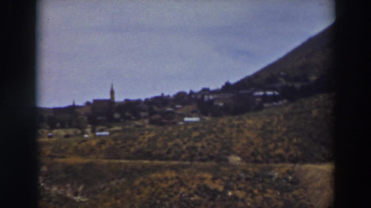 Truckee townscape on 8mm film, with a steeple and low buildings spread across a dry hillside base.