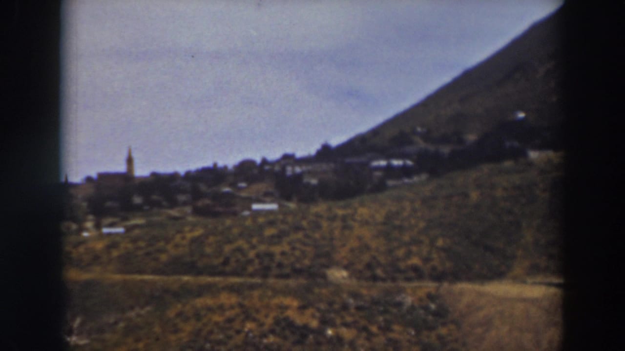 Wide 1937 home-movie frame of Truckee, with a steeple at left and scattered hillside buildings under a pale sky.