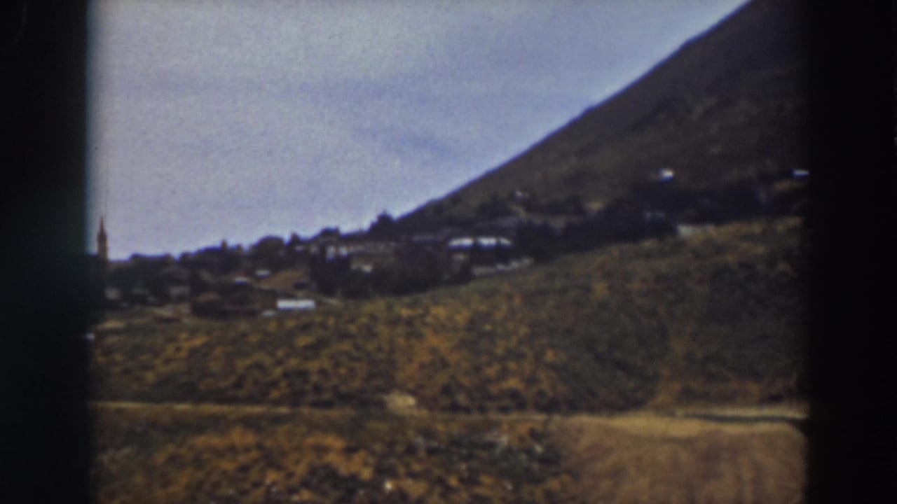 Final 8mm frame of the Truckee hillside town view, with dry terrain, low buildings, and a partial steeple near the left edge.