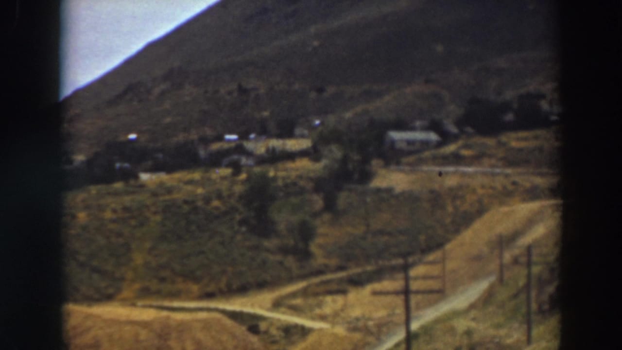 Similar valley view with hillside, homes, road, and utility poles.