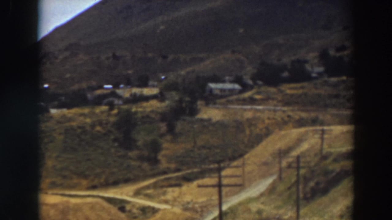 Home-movie view of a rural Truckee hillside area, with dirt roads crossing open land near houses and telephone poles.
