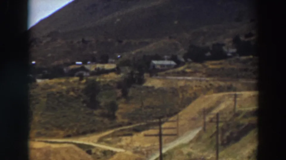 Home-movie view of a rural Truckee hillside area, with dirt roads crossing open land near houses and telephone poles.