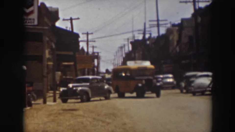 1937 Truckee street view with the yellow bus near the foreground, classic cars parked along both sides, and overhead utility lines above.