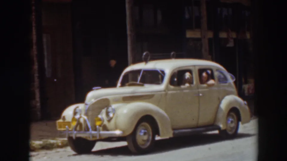 1937 Truckee home-movie still with the cream sedan filling more of the frame, the dog near the front passenger window and the driver visible inside.