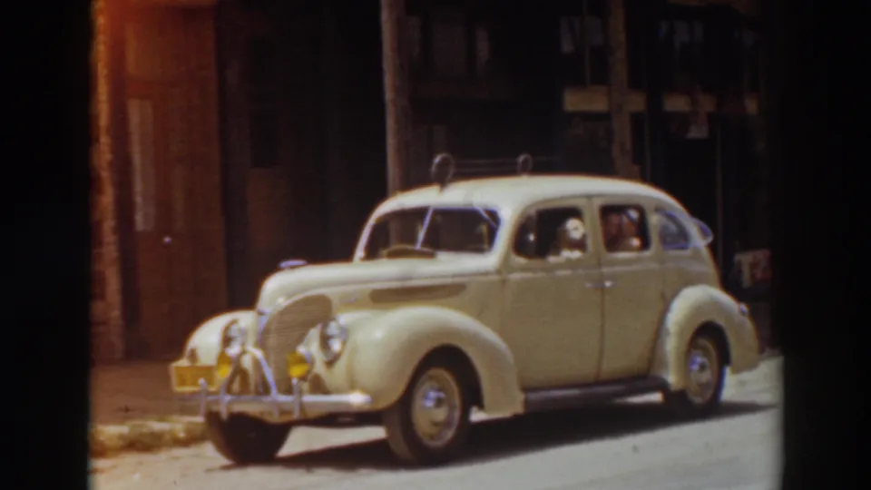 A cream-colored 1930s sedan remains parked on the Truckee street, framed by dark film edges and shadowed building fronts.
