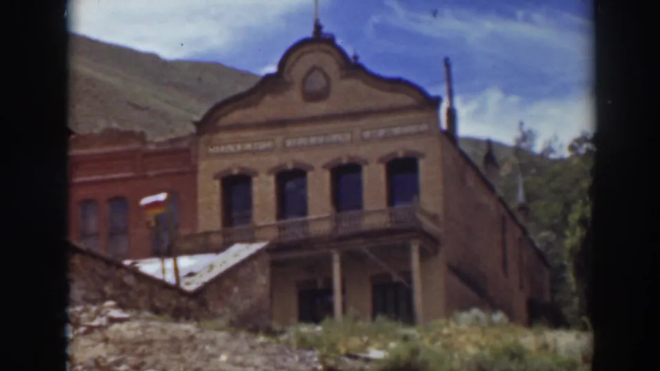 Historic brick commercial building in Truckee with upper facade lettering, balcony, hillside, and clear sky.