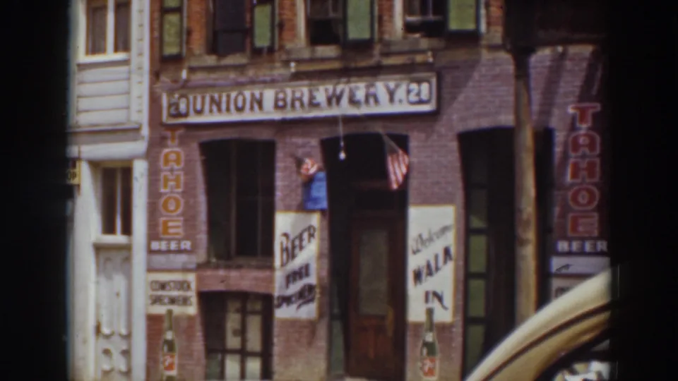 1937 Truckee storefront showing Union Brewery signage, Tahoe Beer advertisements, an American flag, and part of a car fender.