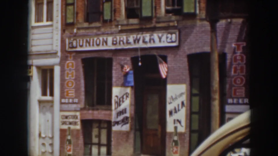 Truckee beer shop exterior showing Union Brewery signage, Tahoe Beer advertising, an entrance flag, and the curved fender of a passing car.