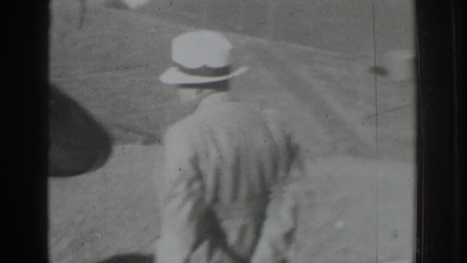 In 1937 Vacaville footage, a man in a light suit and white hat walks away from the camera across open ground.