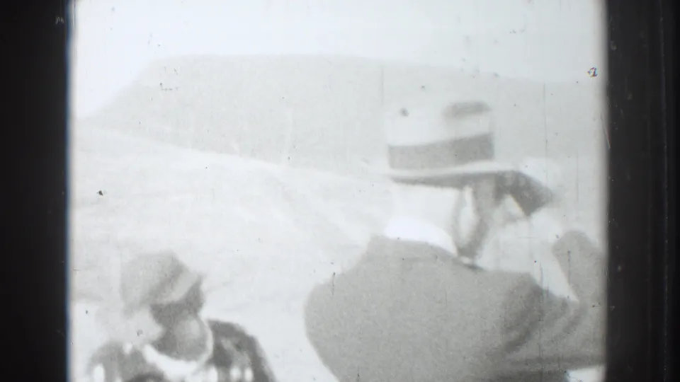 Two adult men in suits and brimmed hats are seen from behind in overexposed 1937 Vacaville home-movie footage.
