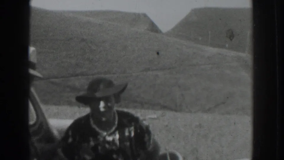 Adult man in a wide-brimmed hat and patterned shirt sits by another man in a suit during a 1937 Vacaville countryside trip.
