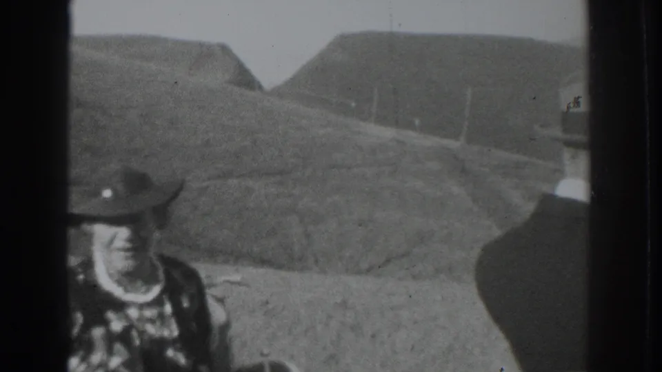 Partial views of two adult men flank a 1937 Vacaville landscape of rolling hills, roadside ground, and bright sky.