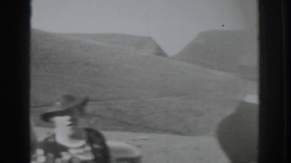 1937 Vacaville frame with a woman in a wide-brimmed hat near a car, set against soft rural hills.